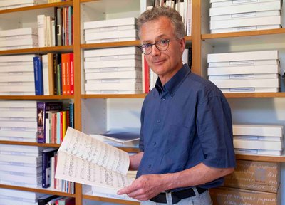 Älterer Mann mit Buch in der Hand im Porträt.